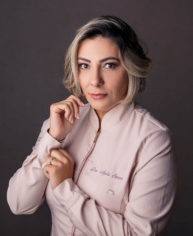 Agda Pires, de jaleco rosa, com a mão junto à gola